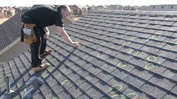 Roofing professional marking damaged areas on roof